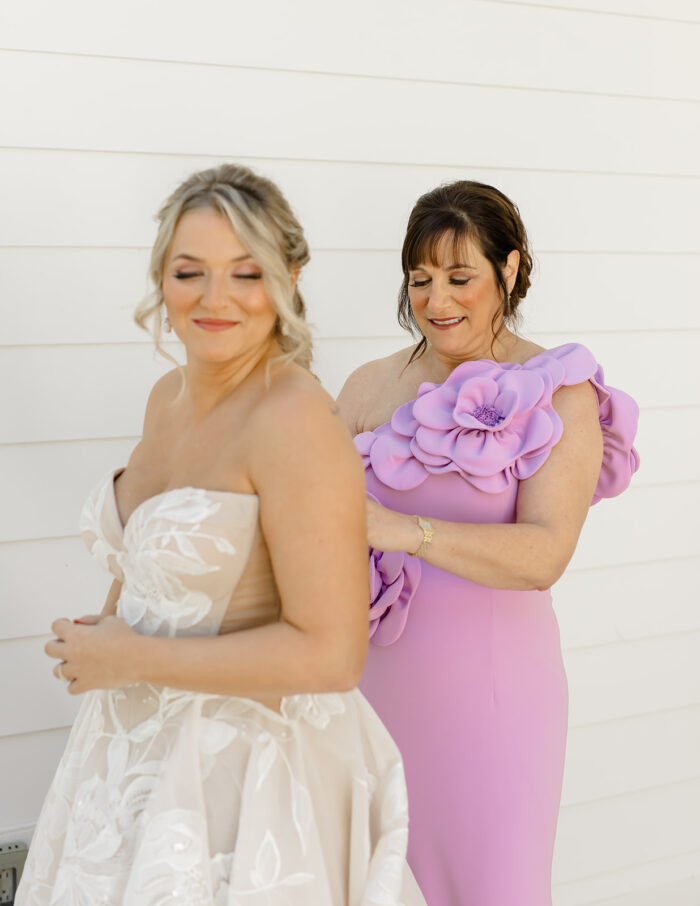 Bride getting ready photos - Mother of bride zipping up her dress.